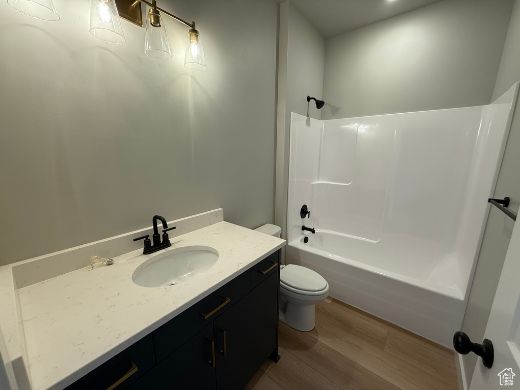 Bathroom featuring toilet, wood finished floors, vanity, and shower / bathtub combination