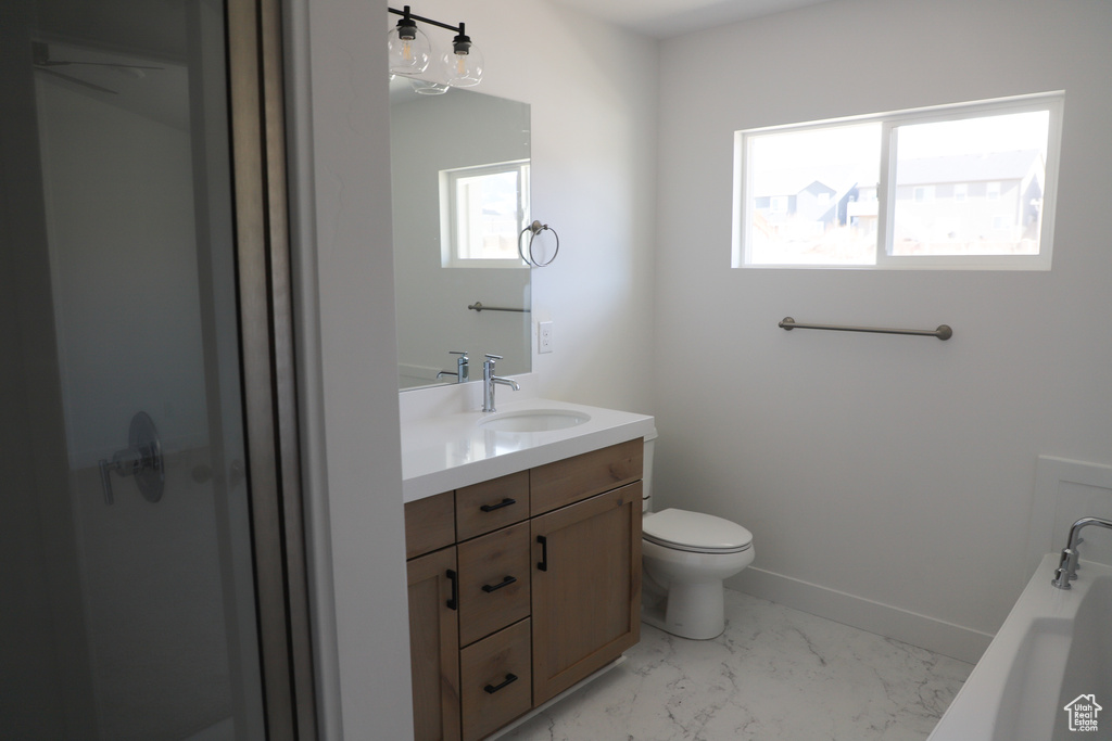 Full bath featuring vanity, toilet, marble finish floor, a tub, and baseboards