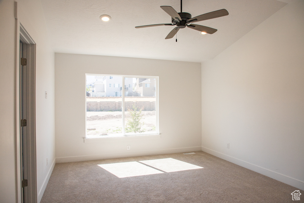 Unfurnished room featuring light colored carpet, ceiling fan, and lofted ceiling