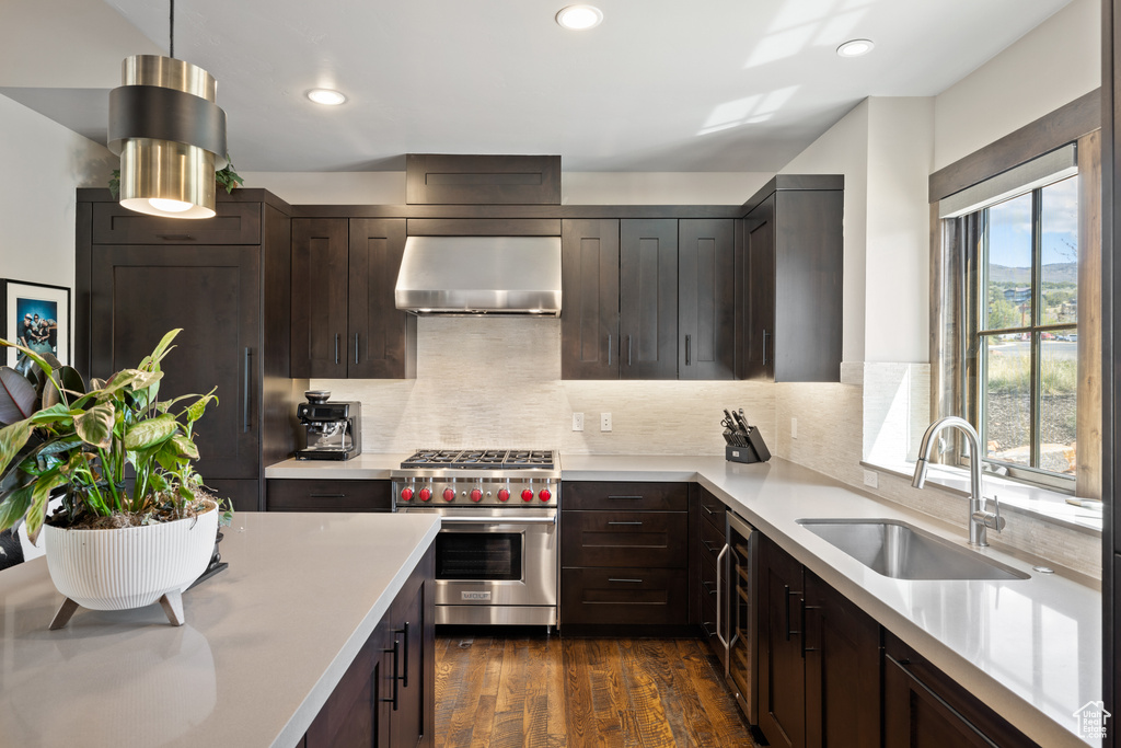 Kitchen featuring dark brown cabinets, a sink, light countertops, designer range, and under cabinet range hood