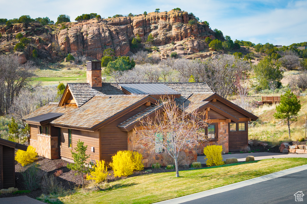 Exterior space featuring a lawn, a chimney, and stone siding