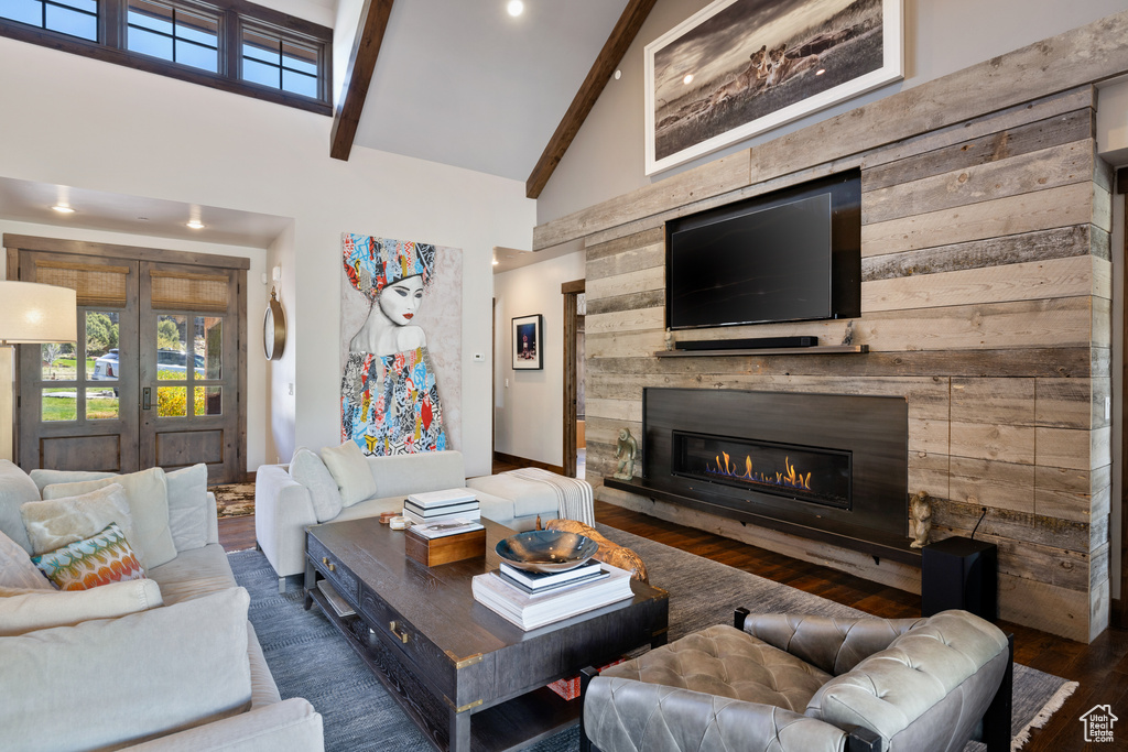 Living area with french doors, beam ceiling, wood finished floors, high vaulted ceiling, and a glass covered fireplace