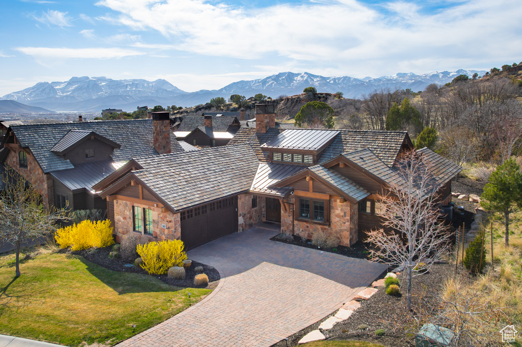 Chalet / cabin with an attached garage, stone siding, a chimney, decorative driveway, and a standing seam roof