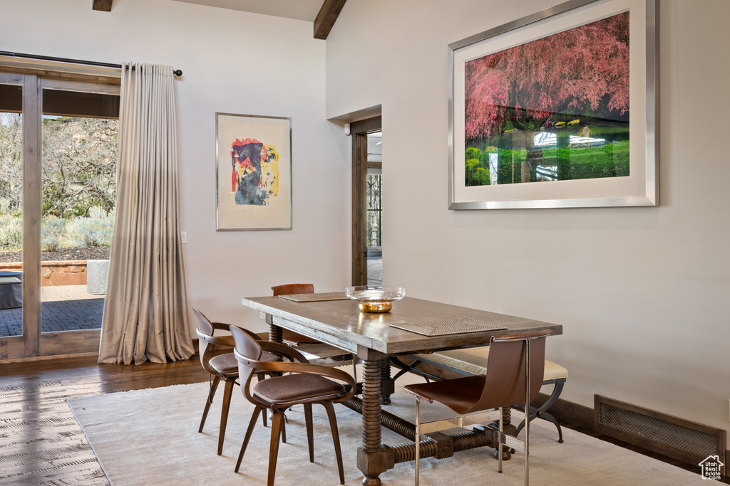 Dining room featuring visible vents, wood finished floors, a wealth of natural light, and beam ceiling