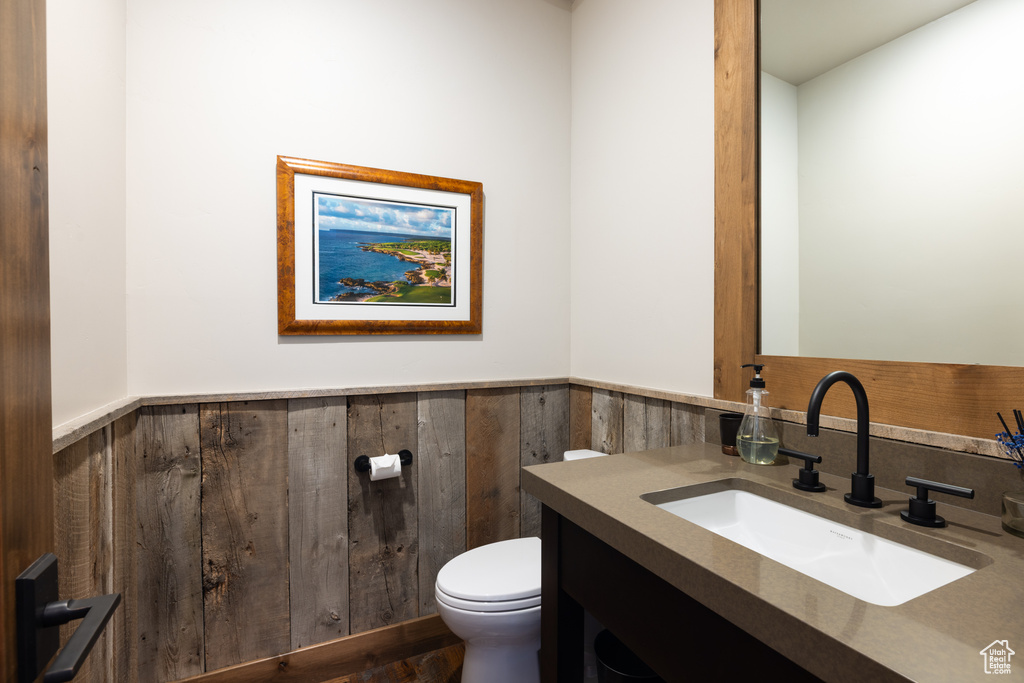 Bathroom with vanity, a wainscoted wall, toilet, and wood finished floors