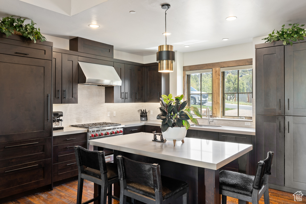 Kitchen with exhaust hood, a kitchen bar, a sink, and light countertops