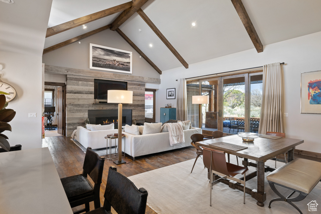 Dining space featuring a lit fireplace, wood finished floors, high vaulted ceiling, beamed ceiling, and recessed lighting