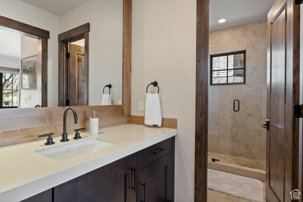 Full bathroom with vanity, decorative backsplash, a shower stall, and recessed lighting