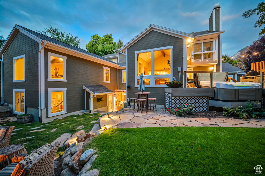 Back of house with a hot tub, a patio, a yard, and a chimney