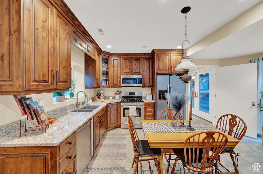Kitchen with brown cabinets, a sink, stainless steel appliances, decorative light fixtures, and recessed lighting