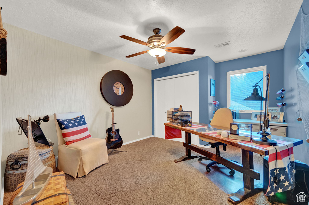 Carpeted home office with baseboards, a ceiling fan, a textured ceiling, and visible vents