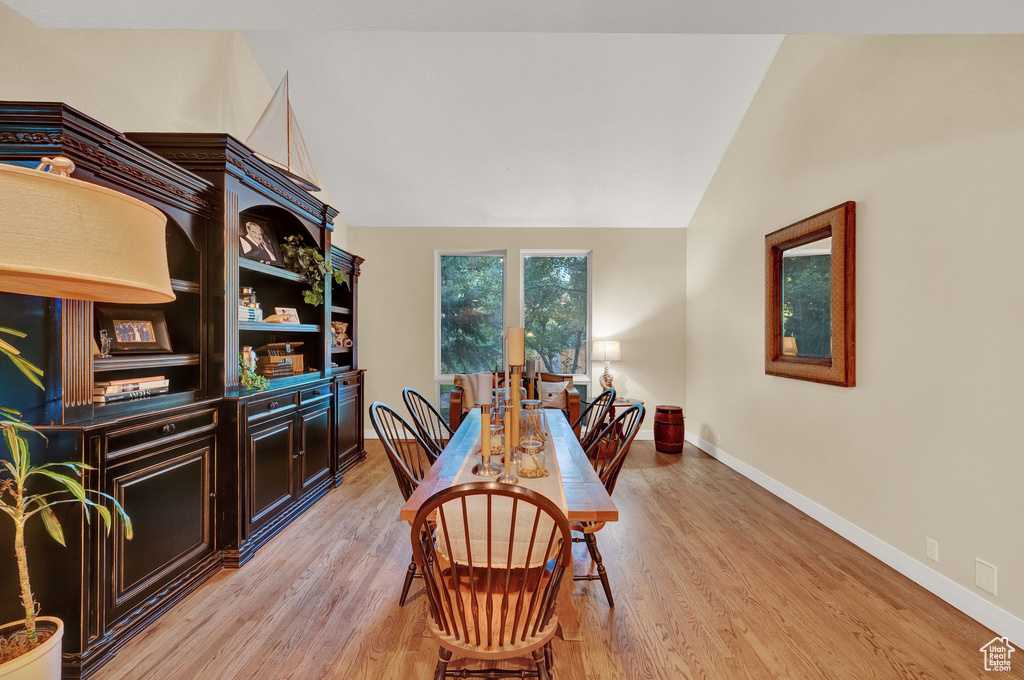 Dining space featuring baseboards, light wood finished floors, and lofted ceiling