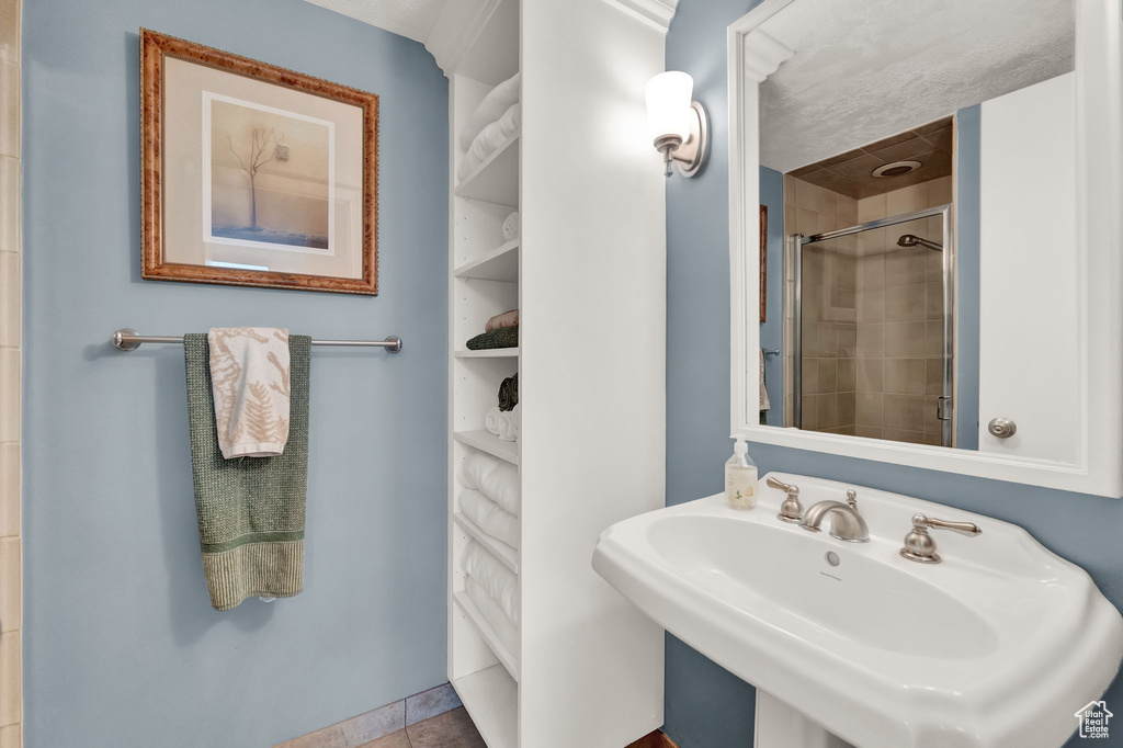 Bathroom with a tile shower, a sink, and tile patterned flooring