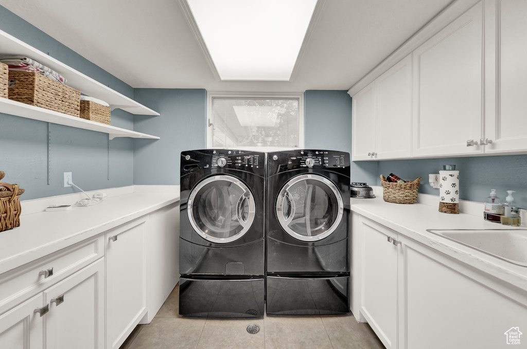 Laundry room with a sink, light tile patterned flooring, cabinet space, and washer and dryer