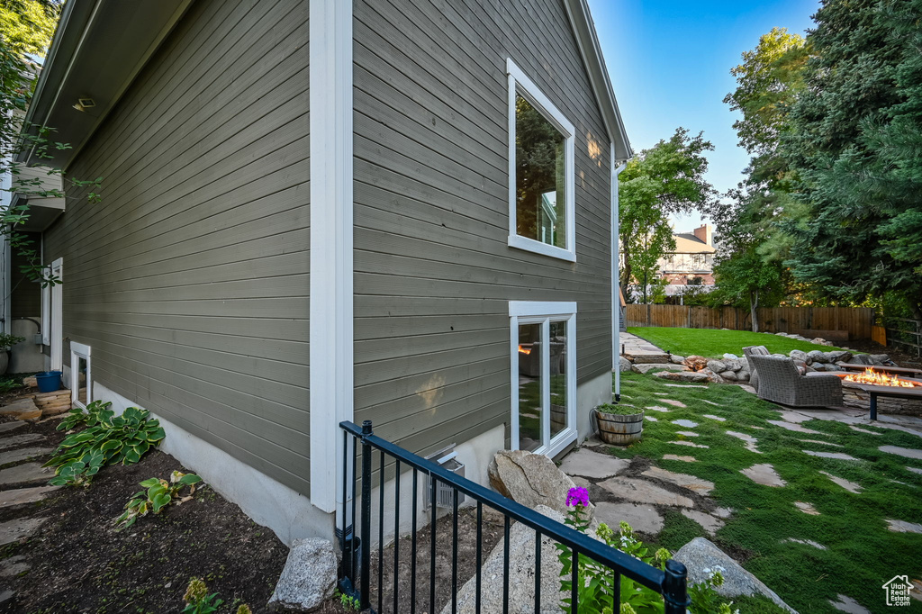 View of home\'s exterior with a patio, an outdoor fire pit, fence, and a yard