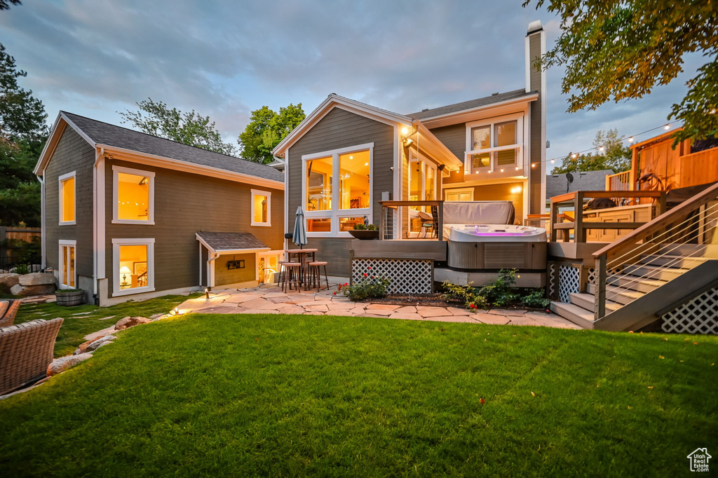 Rear view of property featuring a hot tub, a wooden deck, a chimney, a patio, and a yard