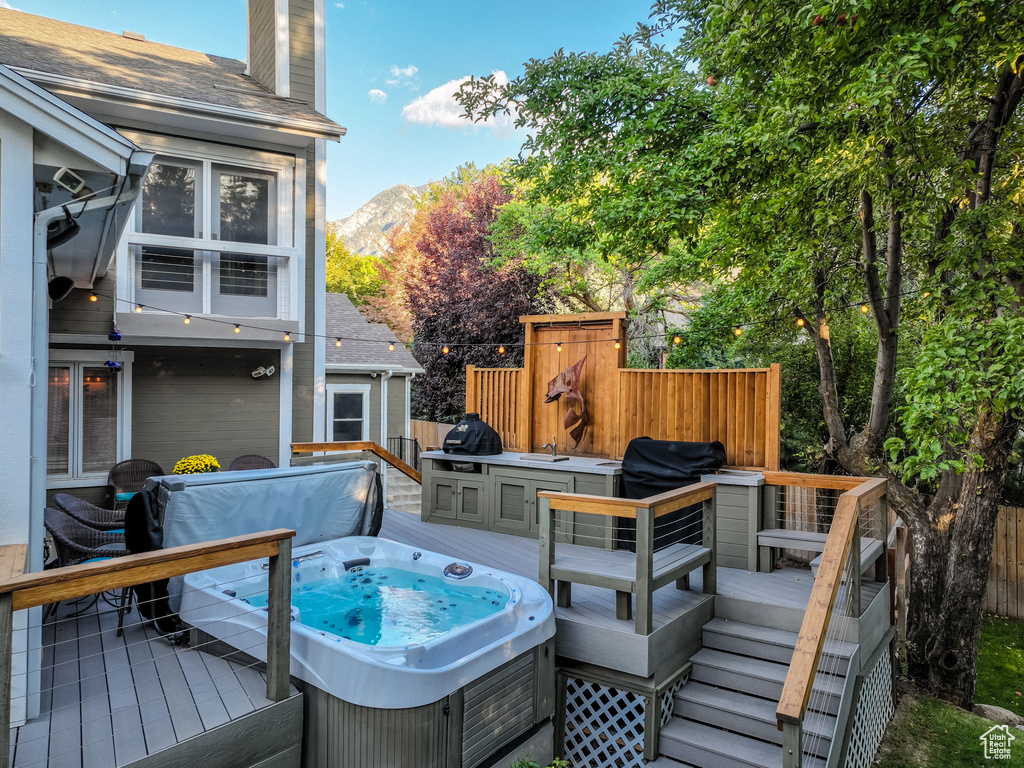 Wooden terrace featuring a mountain view, grilling area, and an outdoor hot tub