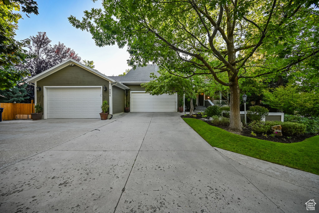 Ranch-style house featuring concrete driveway, fence, and a garage