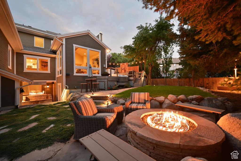 View of patio with fence, an outdoor living space with a fire pit, and a deck