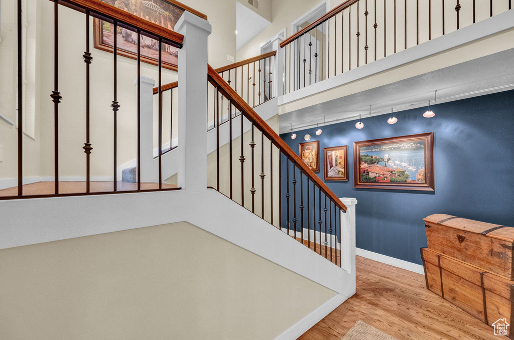 Stairs featuring baseboards, a towering ceiling, and wood finished floors