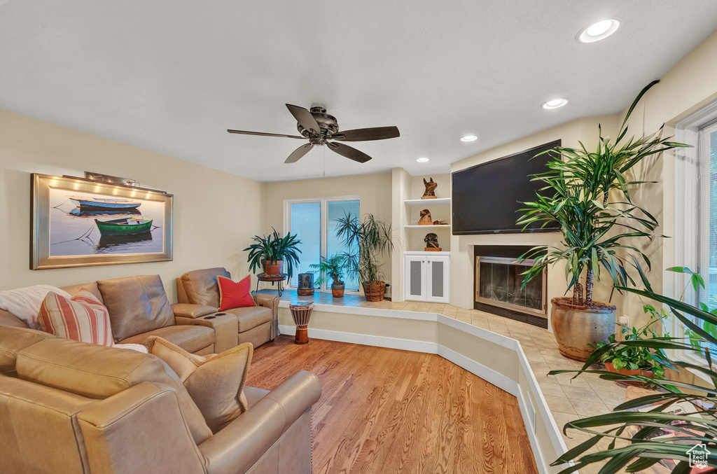 Living area featuring recessed lighting, light wood finished floors, ceiling fan, and a glass covered fireplace