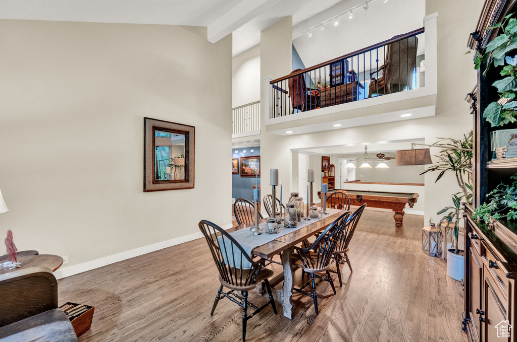 Dining area featuring baseboards, billiards, wood finished floors, and high vaulted ceiling