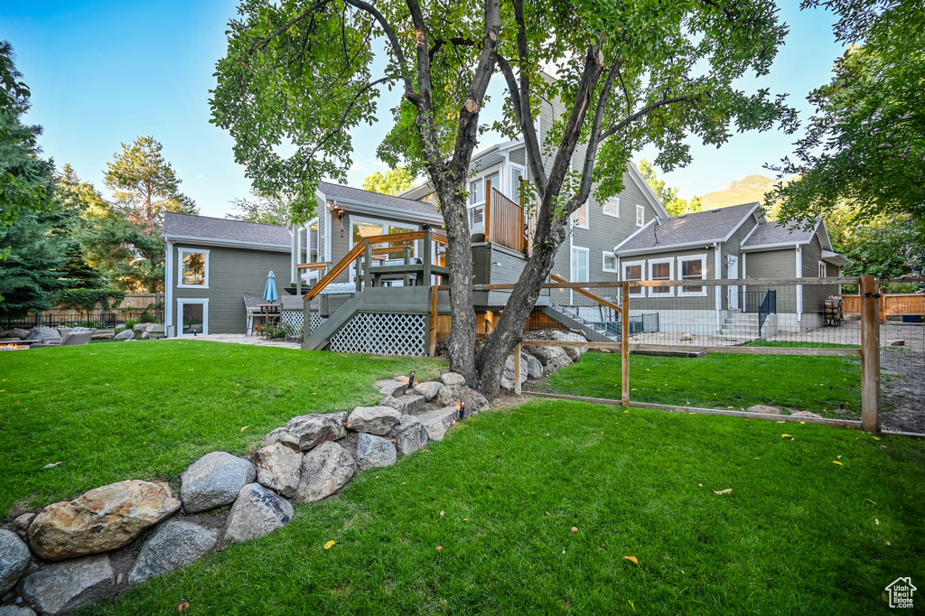 Back of property with stairway, a yard, fence, and a wooden deck