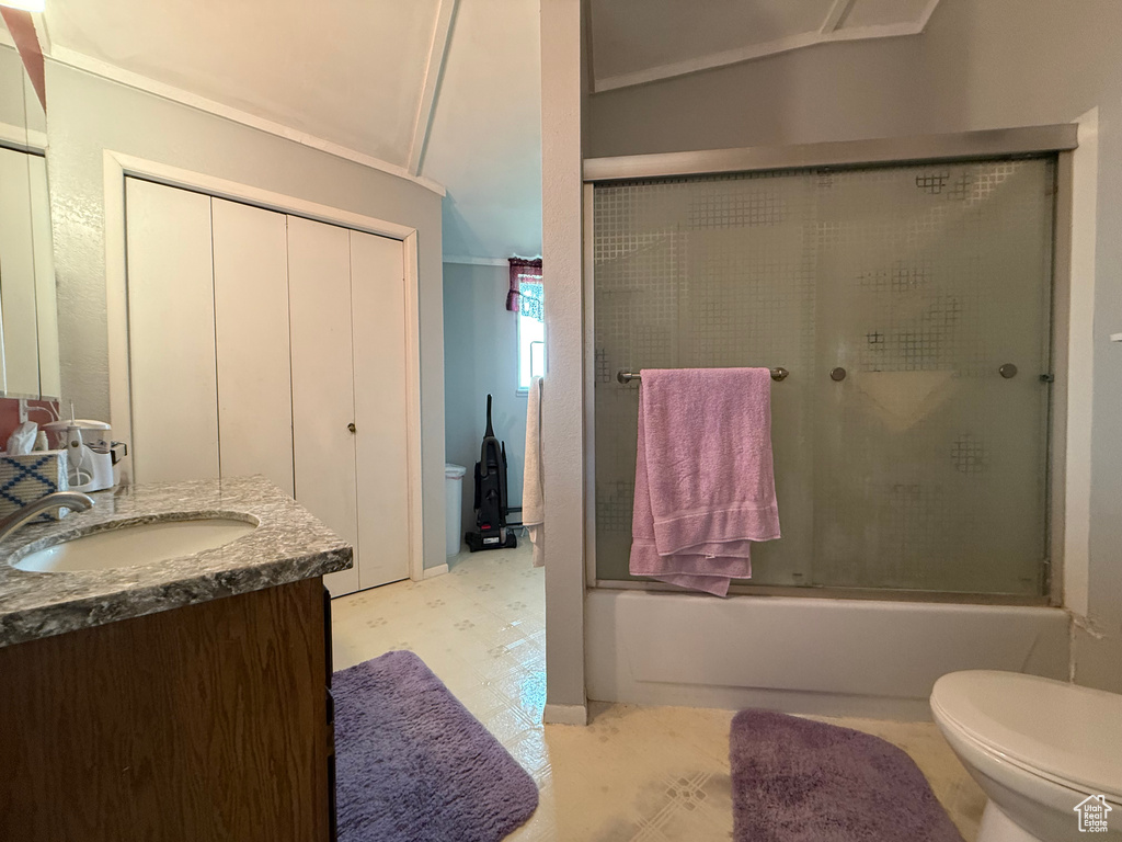 Bathroom with vanity, lofted ceiling, toilet, baseboards, and enclosed tub / shower combo