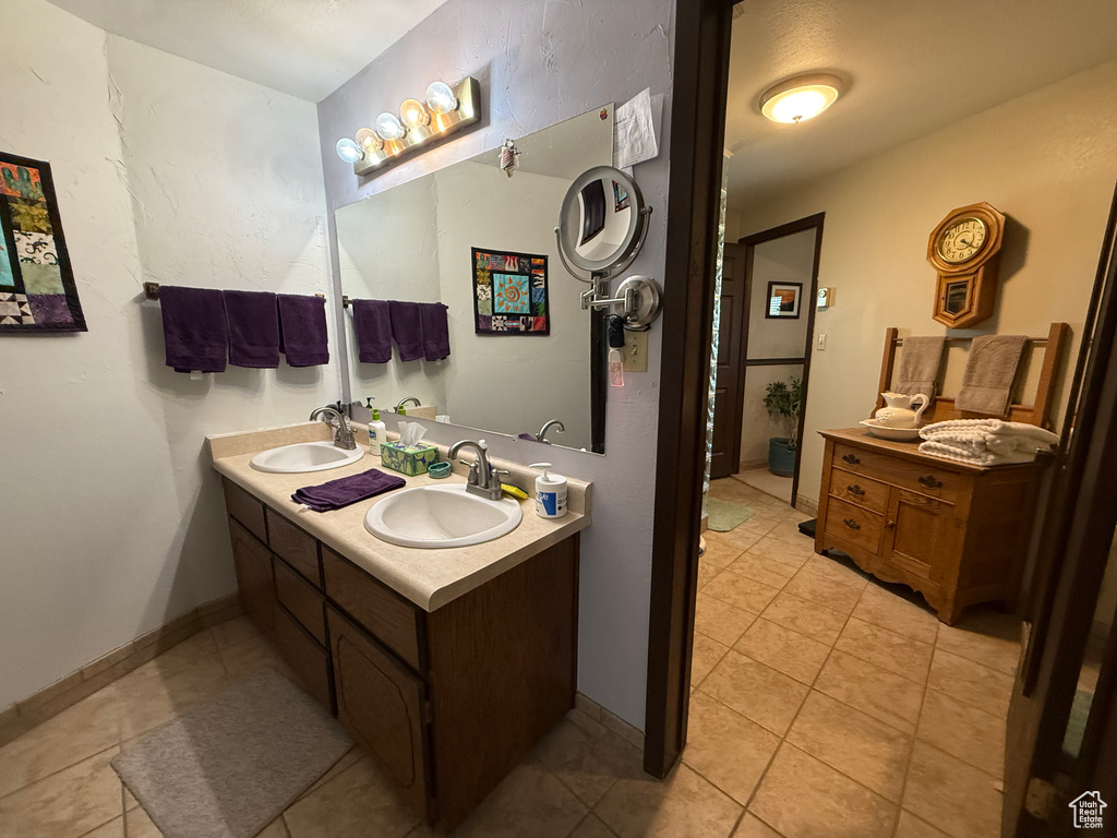 Bathroom featuring double vanity, tile patterned floors, and a sink