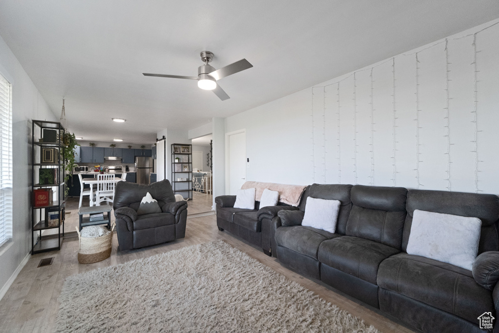 Living room with ceiling fan, visible vents, and wood finished floors