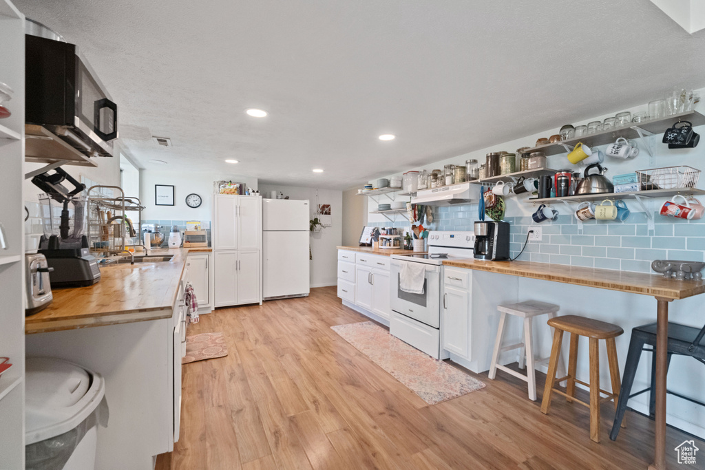 Kitchen with white appliances, open shelves, a sink, and butcher block counters