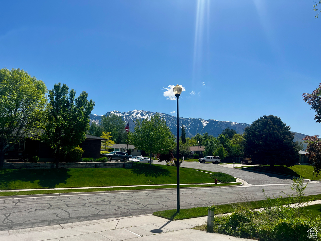 View of asphalt street with sidewalks, a mountain view, and street lights