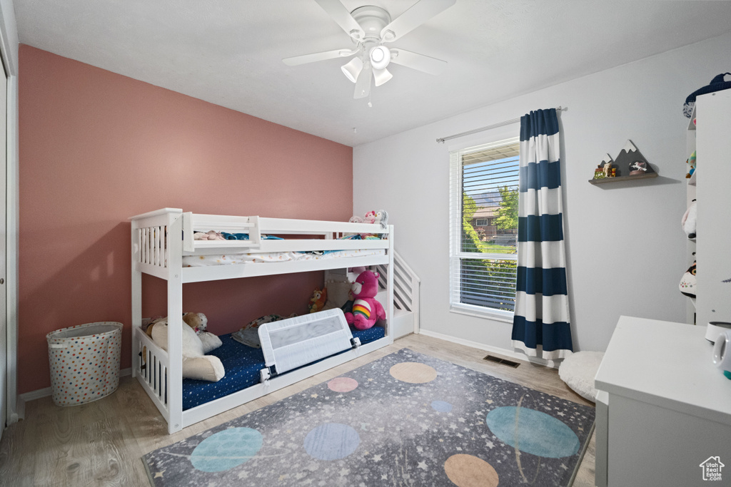 Bedroom with baseboards, ceiling fan, wood finished floors, and visible vents
