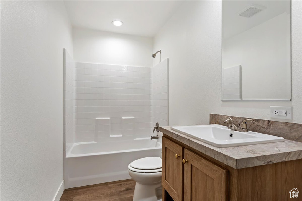 Bathroom featuring vanity, shower / tub combination, wood finished floors, and toilet