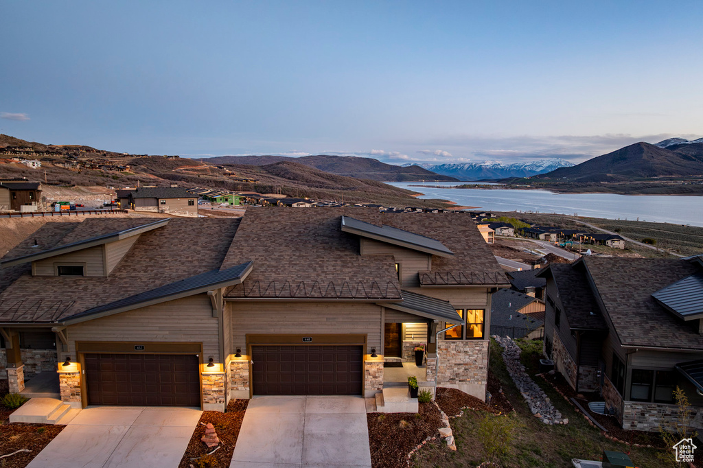 View of front of home featuring roof with shingles, an attached garage, stone siding, a mountain view, and concrete driveway
