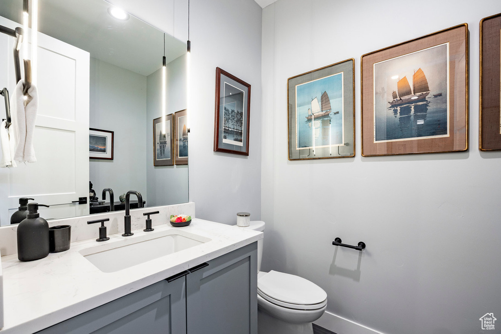Half bathroom featuring vanity, recessed lighting, and toilet