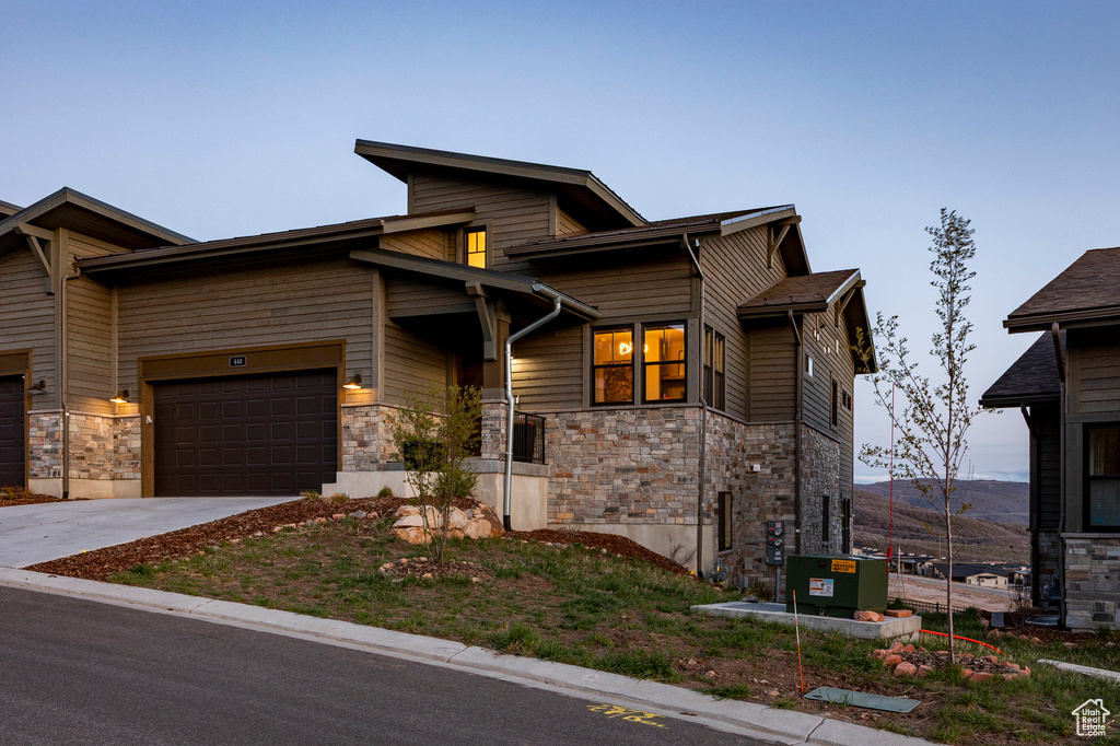 View of front facade with a garage, stone siding, and concrete driveway