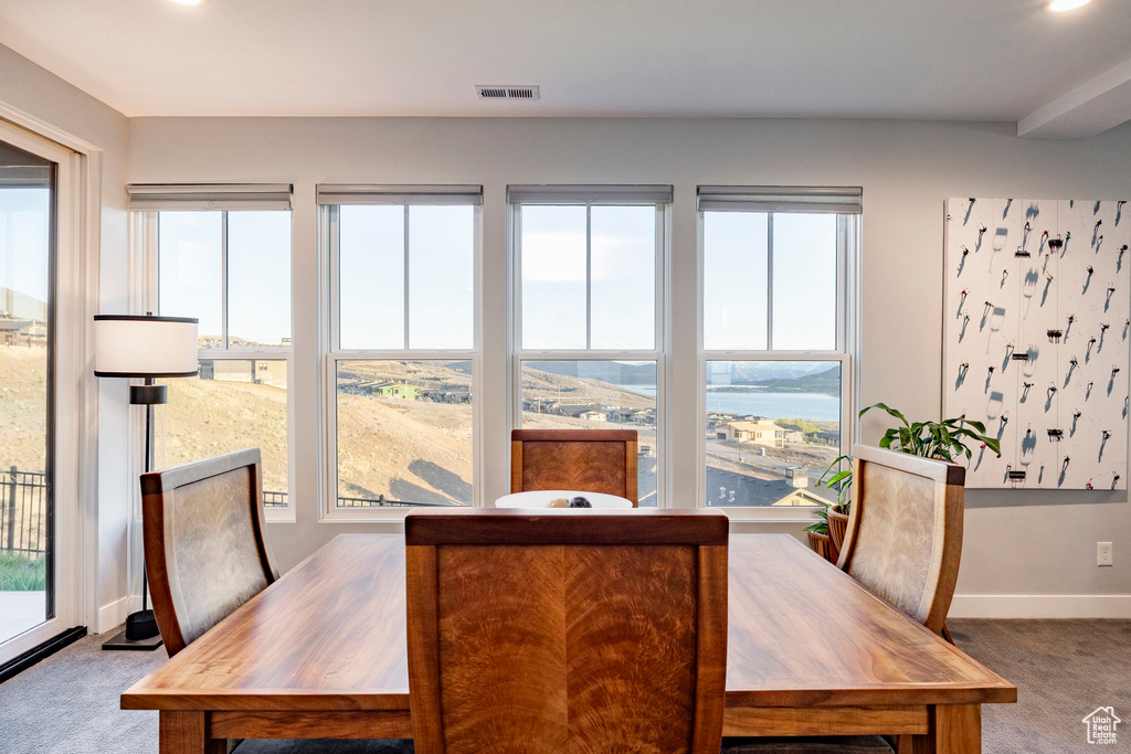 Carpeted dining space featuring visible vents, baseboards, and a wealth of natural light