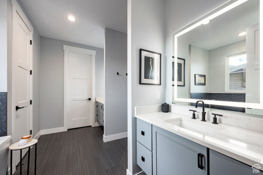 Bathroom featuring baseboards, vanity, recessed lighting, and wood finished floors