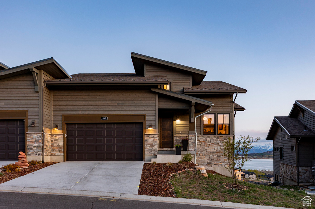 View of front of home with a garage, concrete driveway, and stone siding