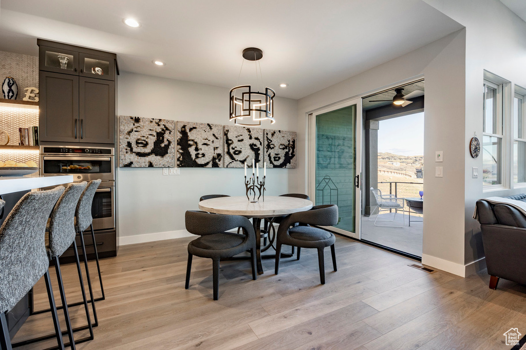 Dining area with light wood-style floors, baseboards, ceiling fan with notable chandelier, and recessed lighting