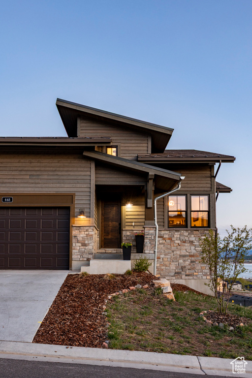 Prairie-style home with a garage, driveway, and stone siding