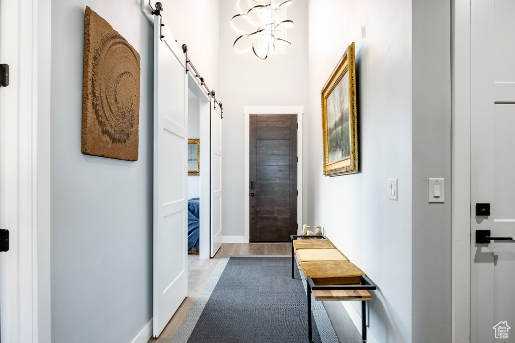 Hall featuring baseboards, a barn door, and wood finished floors
