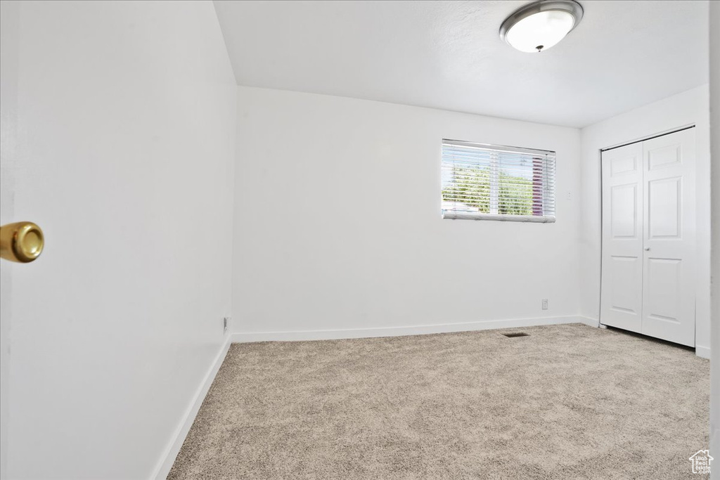 Unfurnished bedroom with carpet flooring, baseboards, visible vents, and a closet