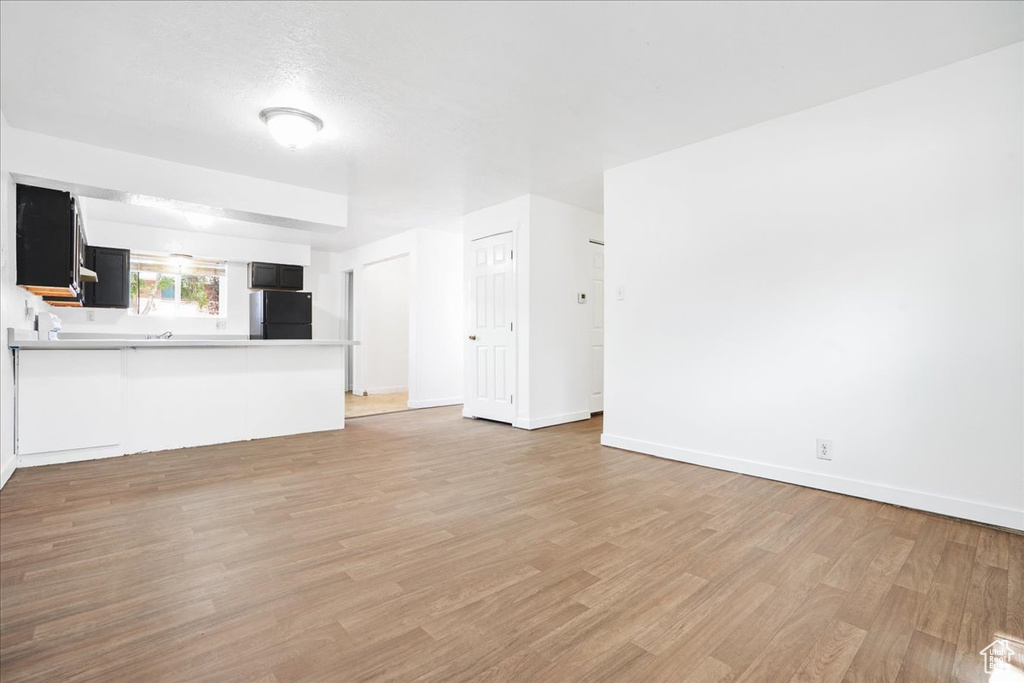 Unfurnished living room with baseboards and light wood-type flooring