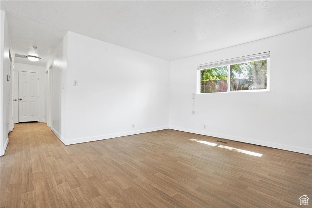 Spare room featuring baseboards and light wood-type flooring