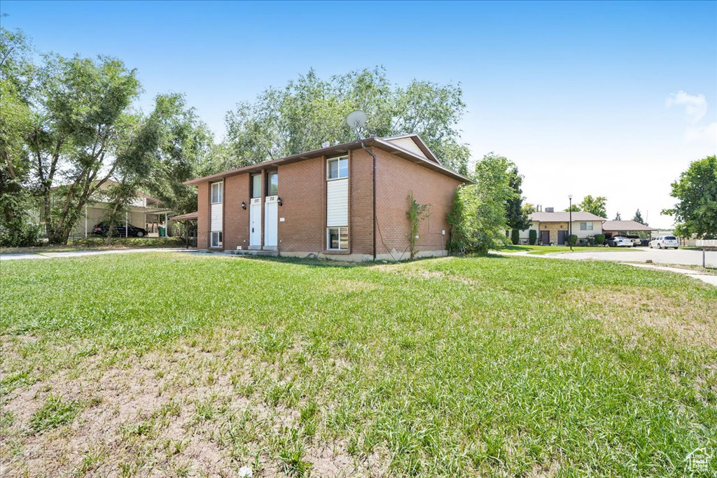 View of property exterior featuring a yard and brick siding
