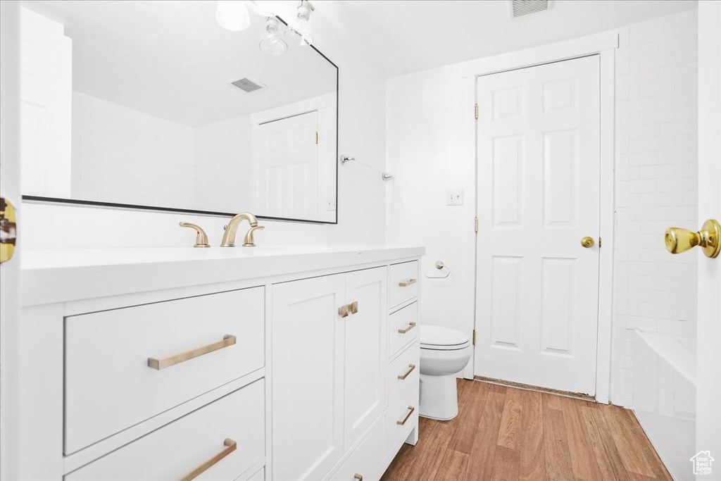 Bathroom with vanity, a washtub, toilet, and wood finished floors