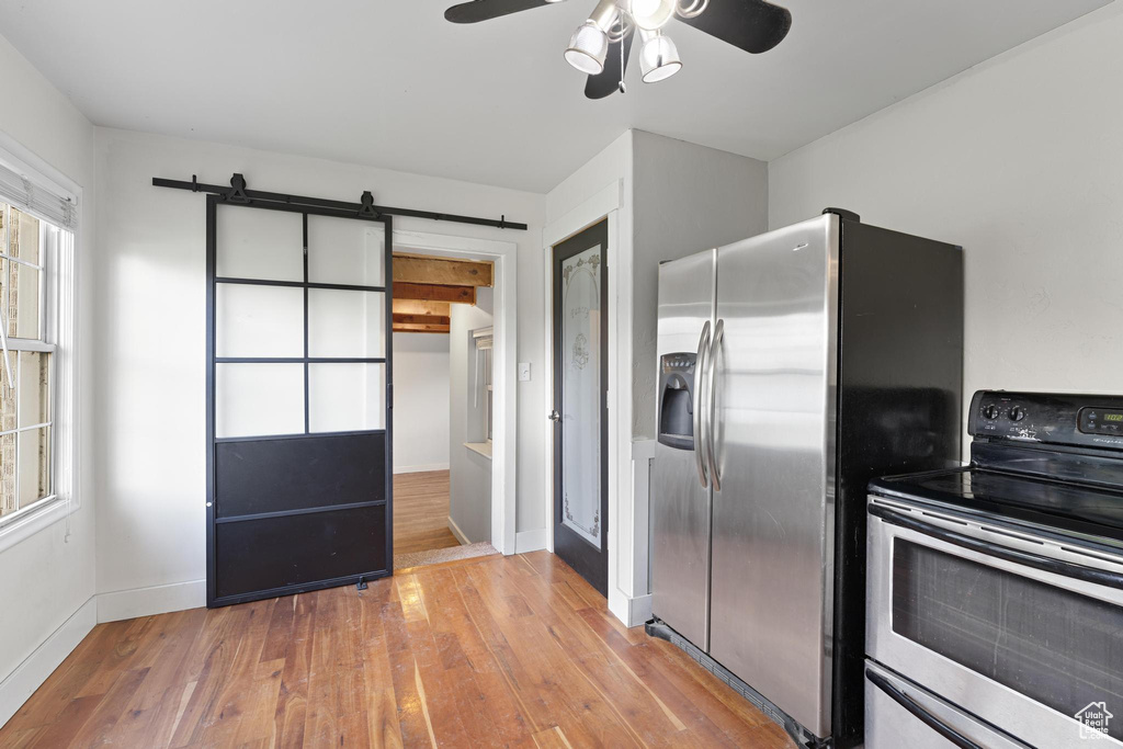 Kitchen with baseboards, stainless steel appliances, a ceiling fan, and wood finished floors