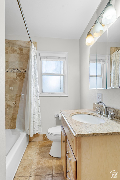 Bathroom with toilet, stone finish floor, shower / tub combo with curtain, and vanity